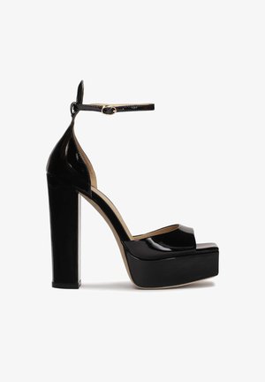 Chaussures plateforme à talons hauts en cuir verni noir avec un design à bout ouvert et une sangle à la cheville, dotées d'un talon carré robuste.