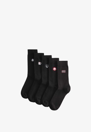 Fünf Paar schwarze Socken, jeweils mit einem kleinen, gestickten Glücksspiel-Motiv: Würfel, Spielkarten, Hufeisen, Pokerchip und ein Spielautomaten-Symbol 777.