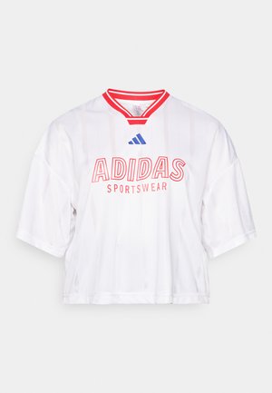 Biała, krótka bluza dresowa z czerwonymi akcentami i paskami, z napisem "ADIDAS SPORTSWEAR" w wyraźnym czerwonym kolorze oraz niebieskim logo na kołnierzyku.