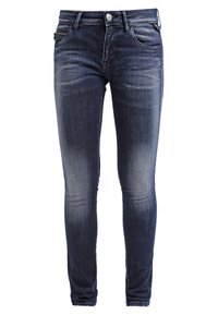 Jean skinny en denim bleu foncé avec délavage subtil. Comprend un design classique à cinq poches et une poche latérale zippée, fabriqué en coton.