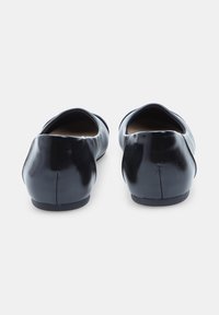 Ballerine di pelle nera con punta arrotondata e tacco basso, caratterizzate da una superficie liscia e un dettaglio di cucitura minimale sul tallone.