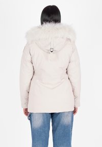 Parka de color rosa claro con capucha de pelo sintético, cintura ceñida y tejido de nailon suave. Presenta detalles de costura y puños elásticos.