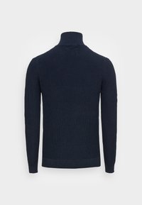 Maglione a collo alto a coste di colore blu navy, con maniche lunghe, mostrato da dietro su uno sfondo bianco.