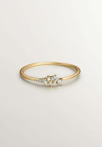 Anillo de oro con una banda delgada, que presenta tres piedras preciosas transparentes dispuestas en un racimo, creando un diseño sutil y brillante.