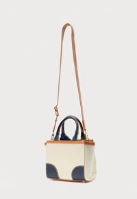Μικρή τσάντα χειρός με κρεμ σώμα, ναυτικό μπλε λεπτομέρειες και λουρί από ταμπά δέρμα. Διαθέτει δύο επάνω λαβές και δομημένο, ορθογώνιο σχέδιο.