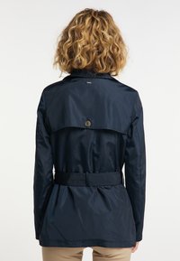Granatowa wodoodporna kurtka z paskiem w talii, szczegółem tylnej kieszeni i lekko rozszerzonym krojem. Gładka tekstura i dopasowany krój.