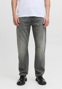 Jeans din denim gri deschis cu o croială dreaptă, prezentând urme ușoare de uzură, cinci buzunare și asortați cu pantofi negri.