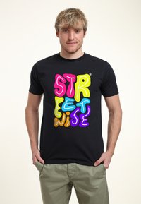Camiseta negra de manga corta con un diseño de texto colorido y oversized en estilo burbuja que dice "STREETWISE" en rosa, amarillo, azul, naranja y púrpura.