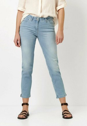 Light blue denim jeans with a fitted design, cropped length, and subtle fading. Paired with strappy brown sandals, showcasing a casual style.