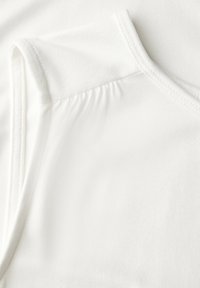 Vit T-shirt med en mjuk textur, med rund halsringning och rynkdetalj vid axelsömmen.