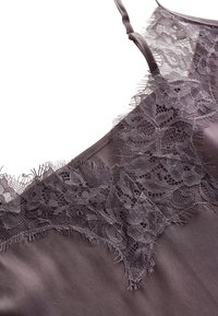 Caraco en satin violet avec bordure en dentelle florale le long du décolleté et fines bretelles.