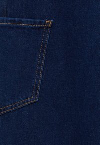 Tissu en denim bleu foncé avec une poche arrière cousue présentant un fil orange et des coutures renforcées aux coins.