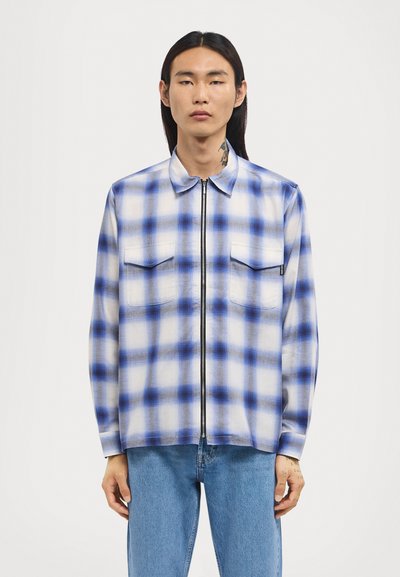 Blau-weißer kariertes Zip-Up-Hemd mit langen Ärmeln und zwei Brusttaschen, aus einem glatten Stoff mit einer leichten Textur gefertigt.