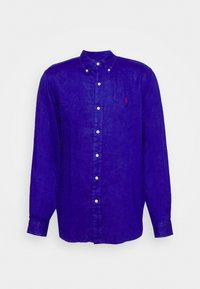 Långärmad knapp-up skjorta i vibrerande kungligt blått linne med krage, med en liten röd logotyp och vita knappar längs framsidan.