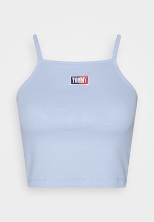 Jasnoniebieski prążkowany krótki top z cienkimi ramiączkami i małą prostokątną naszywką z logo w kolorach granatowym, białym i czerwonym z napisem "TOMMY" umieszczoną na środku klatki piersiowej.