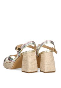 Sandalias de plataforma doradas con tiras de rayas multicolor y tacones de bloque envueltos en yute. Detalle de correa ajustable para el tobillo. Textura suave.
