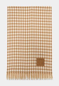 Plaid tissé représentant un motif pied-de-poule en beige et crème, fini avec des bords frangés et une petite étiquette en cuir.