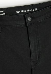 Czarne dżinsy o dopasowanym kroju. Zamek na guzik i przeszycia. Metka marki umieszczona wewnątrz pasa brzmi "Diverse Jeans 38".