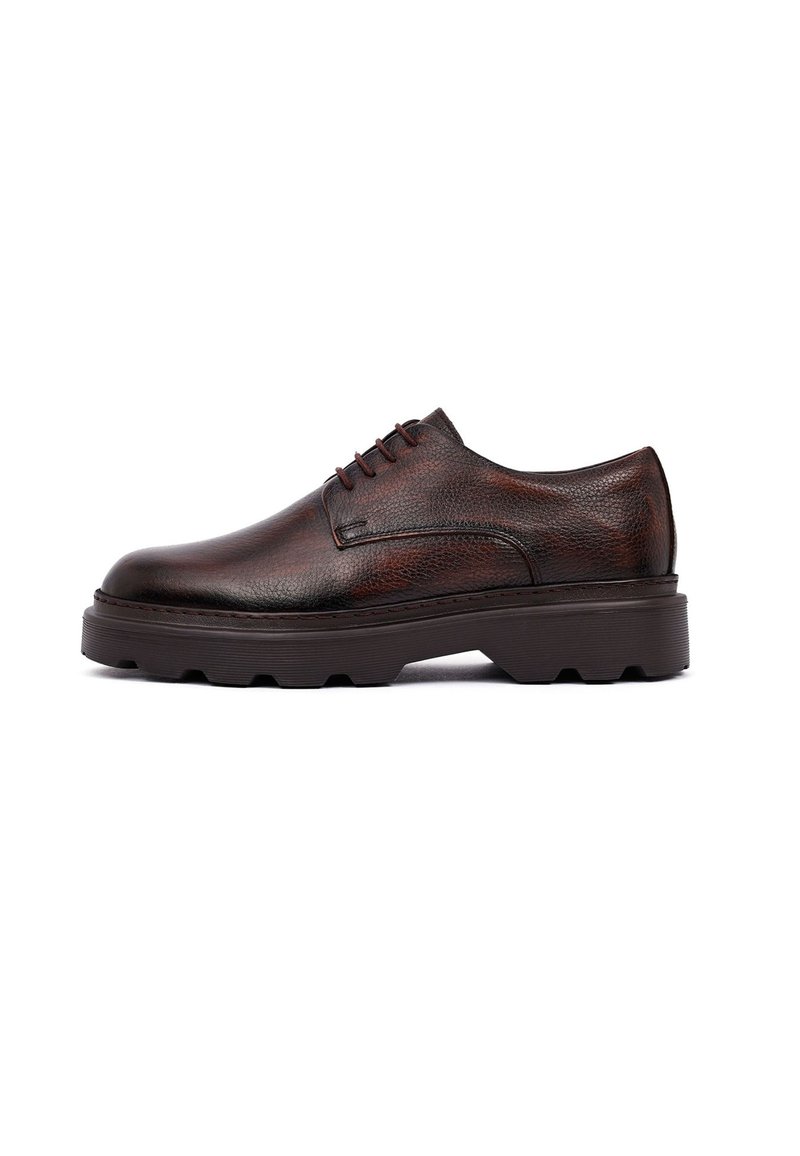 Zapato de vestir de cuero marrón con un acabado texturizado, puntera redondeada y cierre con cordones de cinco ojales. Suela de goma gruesa con detalles de tracción.