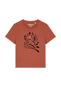 Roestbruine t-shirt met korte mouwen, featuring een zwart lijntekening van een zittende figuur, omringd door bloemen- en hemelse elementen.
