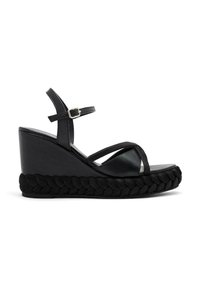 Sandalia de cuña negra con plataforma trenzada y tiras delgadas. Ajuste con hebilla; textura suave y diseño angular. Construida para la estabilidad.