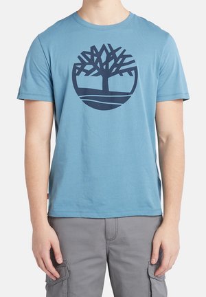 Jasnoniebieska bawełniana koszulka z krótkim rękawem, z okrągłym logo drzewa w granatowym kolorze. Okrągły dekolt.