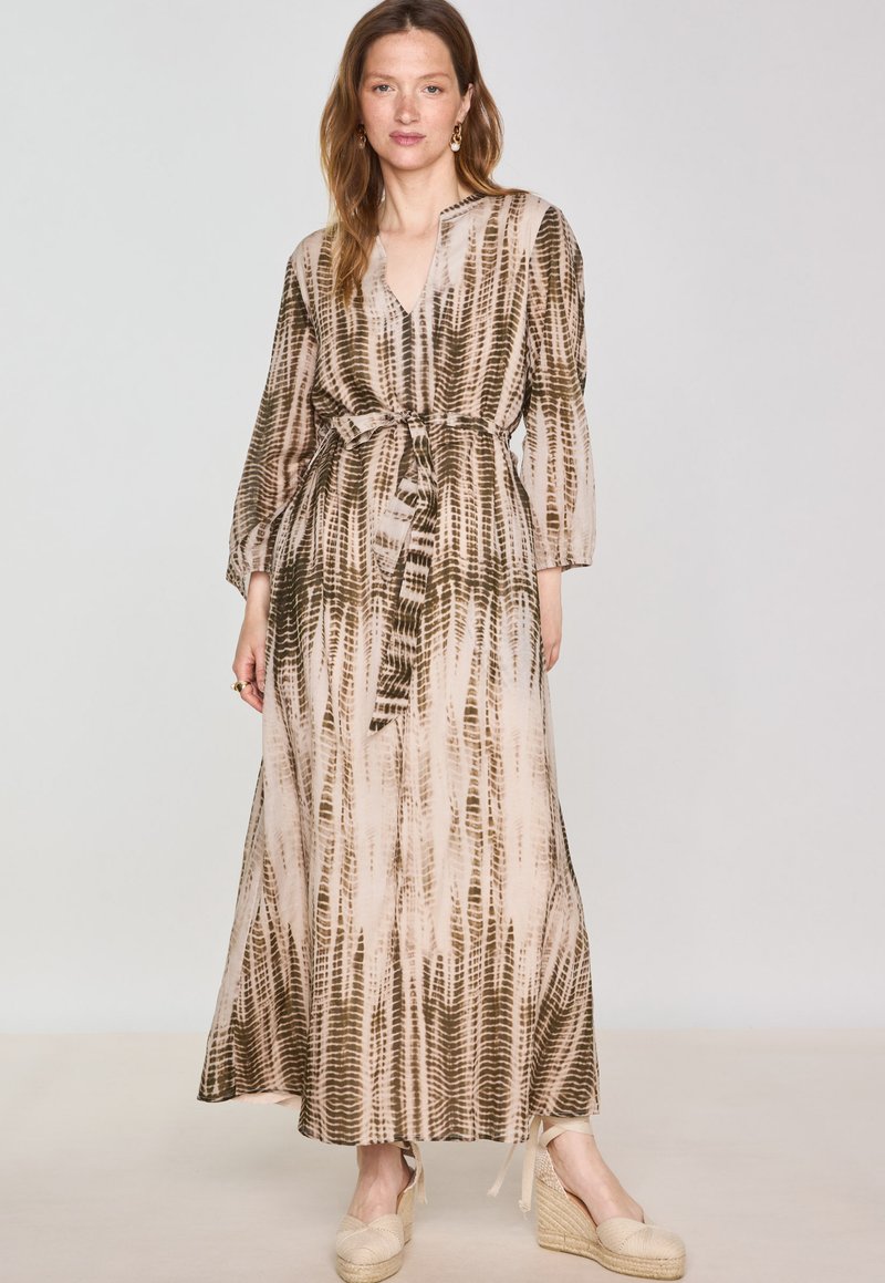 Lungo vestito di colore neutro con cintura in vita, scollatura a V e maniche lunghe; presenta un motivo testurizzato marrone e beige.