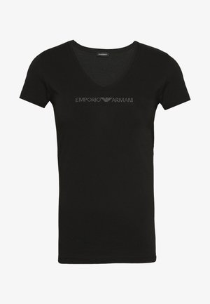Camiseta negra de manga corta con escote en V. Presenta "EMPORIO ARMANI" en tachuelas metálicas a lo largo del pecho. Textura de tela suave.