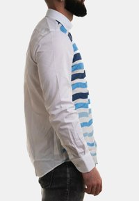 Camicia bianca con motivo a righe blu su un lato, con colletto classico e polsini abbottonati, realizzata in un tessuto leggero.