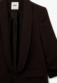 Blazer para mujer de color marrón oscuro con cuello chal, mangas largas, bolsillos delanteros con solapa y un forro interior negro liso.