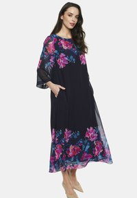 Luźna, ciemnoniebieska sukienka z kwiatowym różowym i purpurowym wzorem. Posiada szerokie rękawy, okrągły dekolt oraz kieszenie. Lekką, przezroczystą tkaninę.