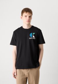Sort bomulds t-shirt med et farverigt logo i blå og pink nuancer. Klassisk rund hals og korte ærmer, afslappet pasform.
