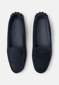 Ciemnoniebieskie zamszowe mokasyny z wyszywanym wzorem i miękką teksturą. Posiadają płaską podeszwę i minimalistyczne akcenty.