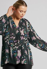 Top a maniche lunghe in tessuto leggero e trasparente con un motivo floreale in tonalità di verde, viola e blu, con scollo a V e silhouette fluida.