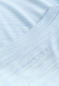 Tessuto activewear azzurro chiaro con una consistenza liscia e linee orizzontali sottili. Presenta un marchio "ACTIVE" in rilievo.