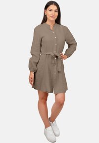 Abito khaki con bottoni e colletto alla mandarina, maniche lunghe a sbuffo e una cintura in vita. Tessuto morbido e strutturato con una vestibilità rilassata.