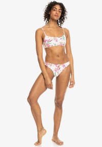 Blomsterbikini sæt med en lyserød baggrund og grønne samt røde bladmønstre. Toppen har tynde stropper; bunden har en lavtaljet skæring.