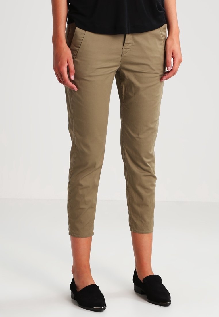 Beige beskurna byxor med två framfickor, en smal passform och ett mjukt bomullsmaterial. Kombination med svarta platta skor.
