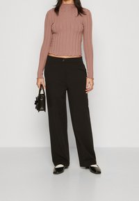 Fitted ribbed long-sleeve top in mauve with scalloped hem, paired with wide-leg black pants and black purse with floral detail, and black flats.