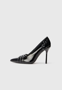 Pantofii cu toc stiletto din piele lăcuită neagră, cu vârf ascuțit, trei curelușe decorative cu nituțe și branding "Karl Lagerfeld" pe toc.