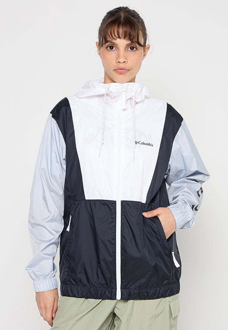 Chaleco ligero con capucha, diseñado con una combinación de colores blanco, azul marino y gris claro. Cuenta con una cremallera frontal, capucha ajustable y puños elásticos.