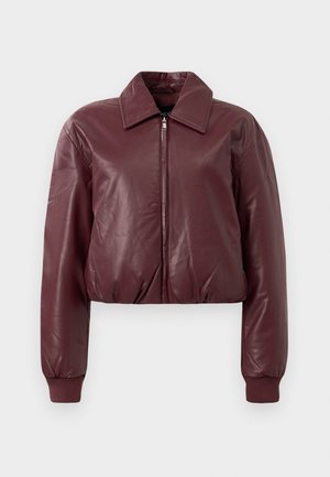 Burgundijas mākslīgās ādas kroptā jaka ar priekšējo rāvējslēdzēju, plašu apkakli, garām piedurknēm un ribotām aprocēm uz vienkārša fona.