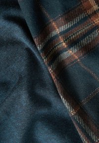 Plaid fabric in dark blue and brown tones, featuring a soft texture. The design includes woven checks with contrasting colors.