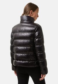Schwarze Daunenjacke mit glänzendem, gestepptem Design und horizontalen Linien, hohem Kragen und lässiger Passform, sichtbar von hinten.