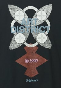 Kuidast must t-särk, millel on valge ja punane disain, kus on kiri "ART DISTRICT" helesinisega, ringikujulised mustrid ja "© 1990" märge.