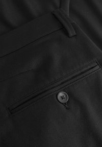 Svart tyg har en platt ficka med en knappdetalj. Texturen är slät och designen inkluderar sydda detaljer längs kanterna.