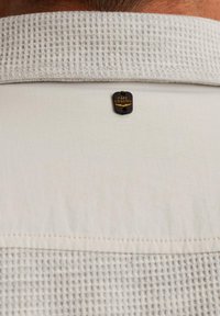 Lichtgekleurde shirt met een gestructureerde witte kraag. Heeft een klein zwart label met het merk "PME Legend" aan de achterkant. Eenvoudige stiksel details.