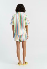 Camicia a maniche corte a righe e pantaloni abbinati in colori pastello, con linee verticali rosa, blu, verde e giallo, realizzati in tessuto leggero.
