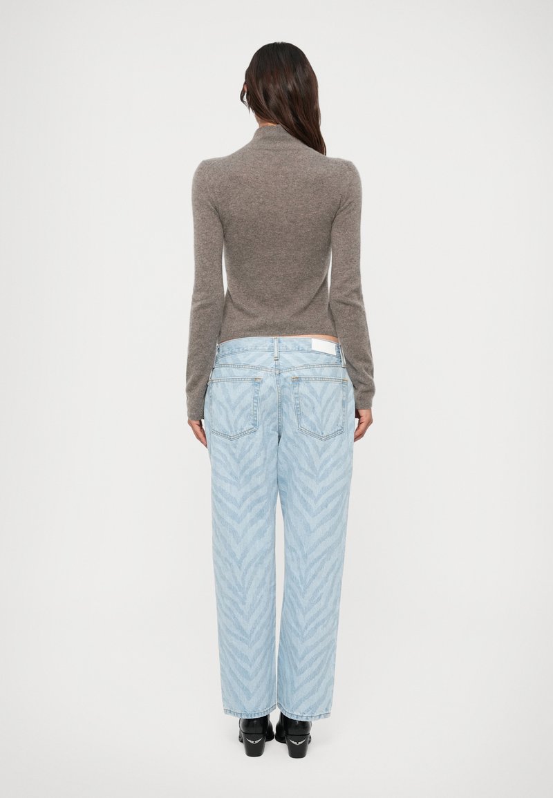 Grijze getailleerde trui met hoge hals, gecombineerd met lichtblauwe wijde jeans met een subtiel zigzagpatroon, en zwarte plateauzolen.