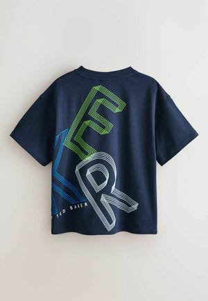 Tamsiai mėlynas medvilninis marškinėlis su dideliu grafiniu tekstu mėlynomis ir žaliomis linijomis, trumpomis rankovėmis ir apvalia iškirpte. Įtrauktas „Ted Baker“ logotipas.